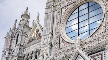 Eine gotische Kathedrale mit aufwendigen Steinschnitzereien, einem großen Rundfenster und einer Statue eines Engels auf dem Dach.