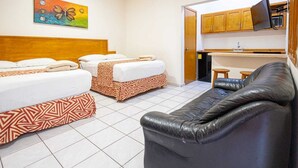 Una habitación de hotel con dos camas, un sofá, un televisor y una zona de cocina.