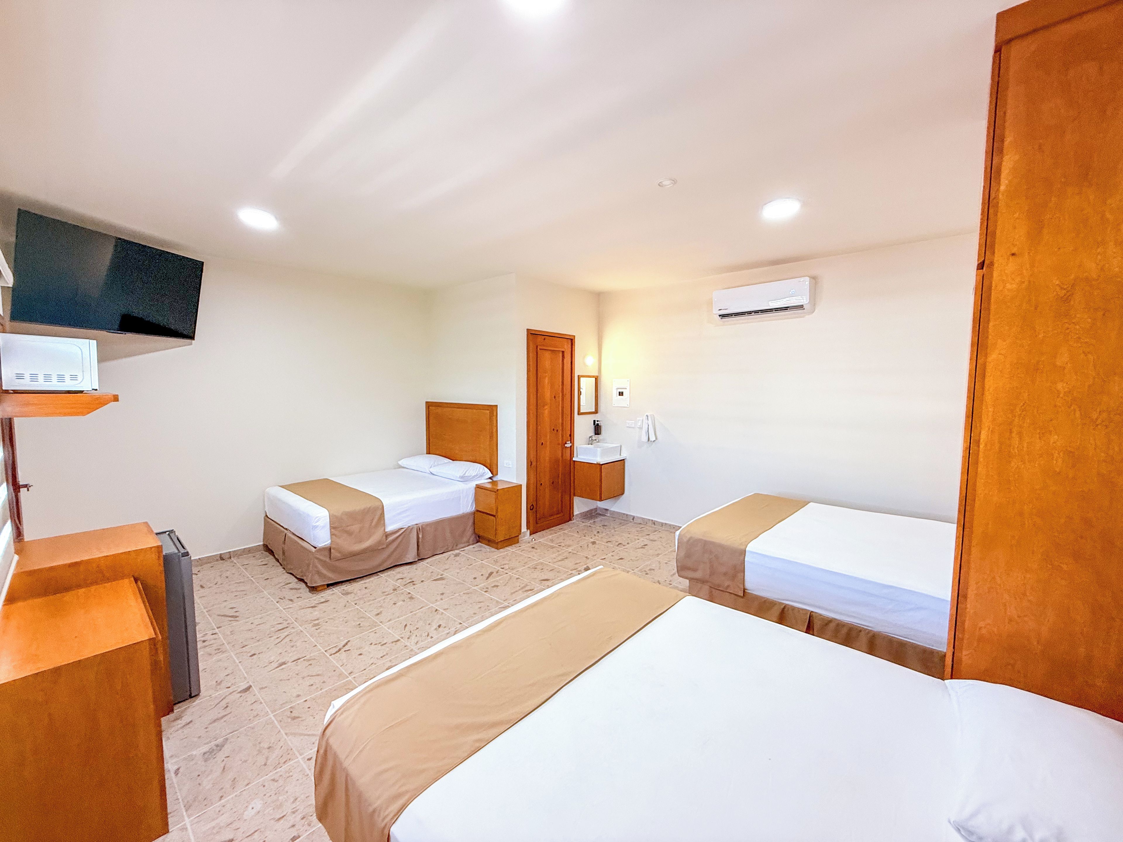 Habitación de hotel con dos camas, televisión, mesita de noche, armario y baño.