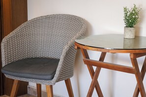Una silla de mimbre con un cojín y una mesita con una planta en maceta.
