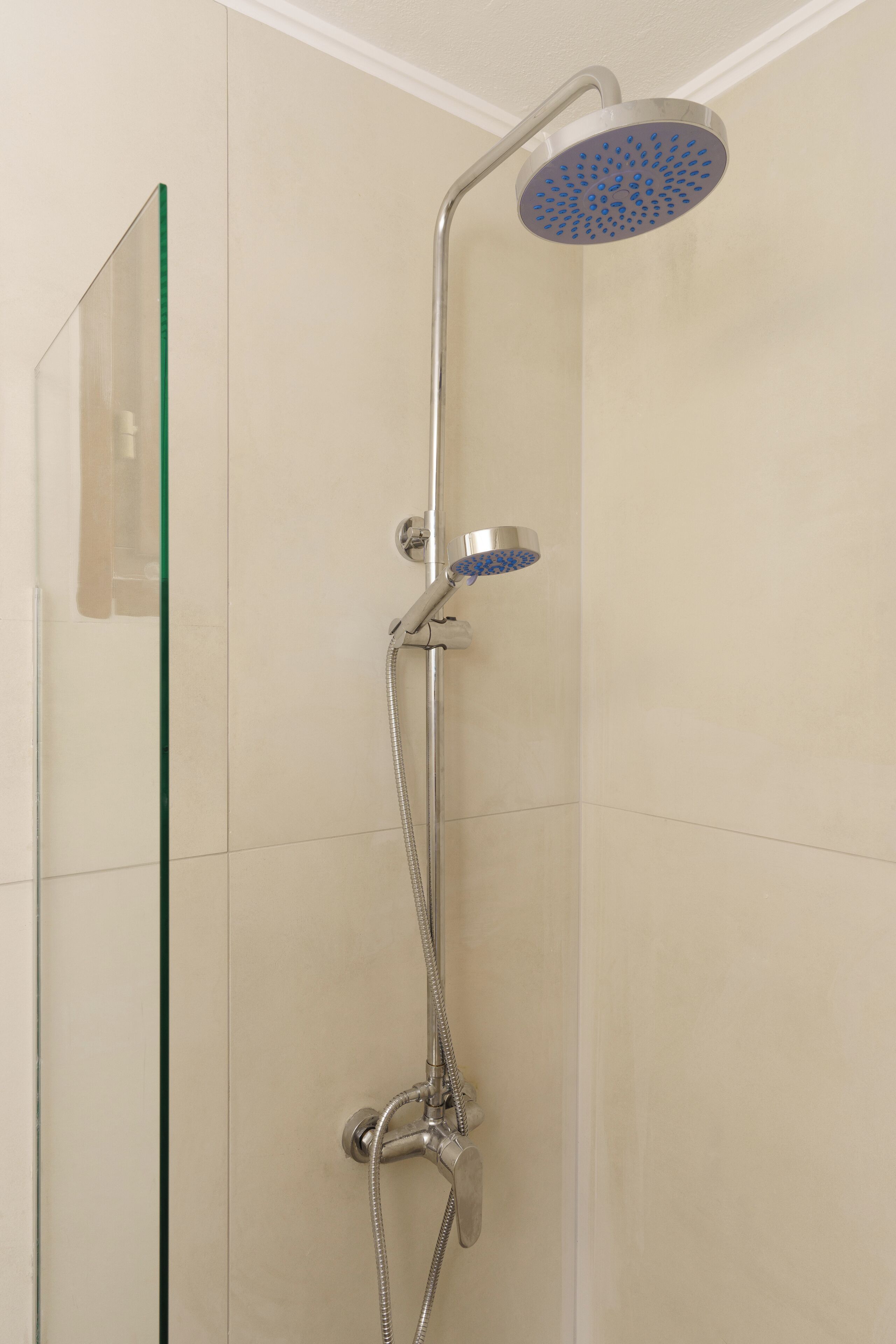 Eine Dusche mit Glasabtrennung, einer Handbrause und einer an der Wand montierten Bedienung.