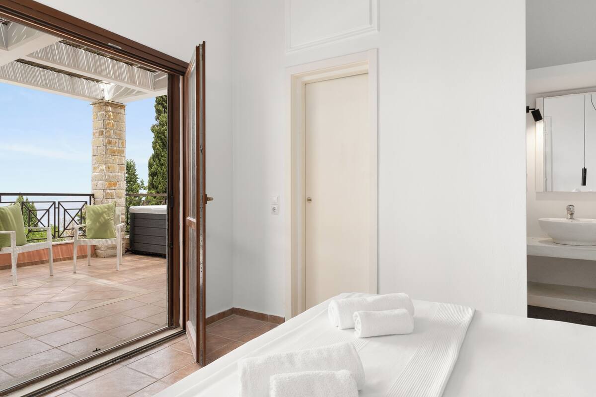 Ein Schlafzimmer mit einem großen Fenster, einer Tür und einem Badezimmer mit einem Waschbecken.