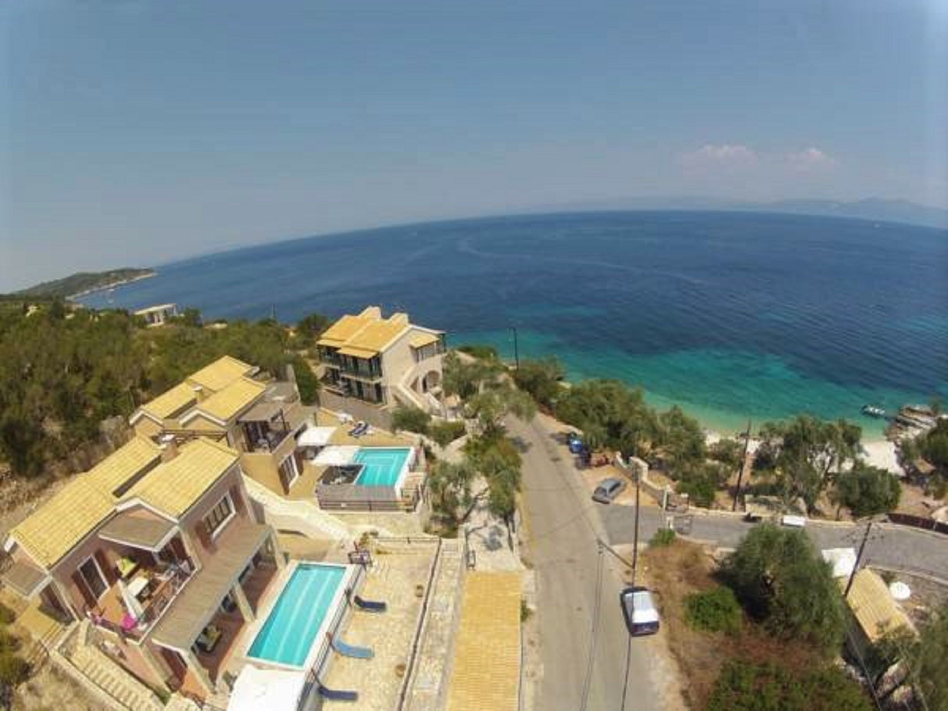 Una propietat a la costa amb piscina, diversos edificis i un camí que condueix a la mar.