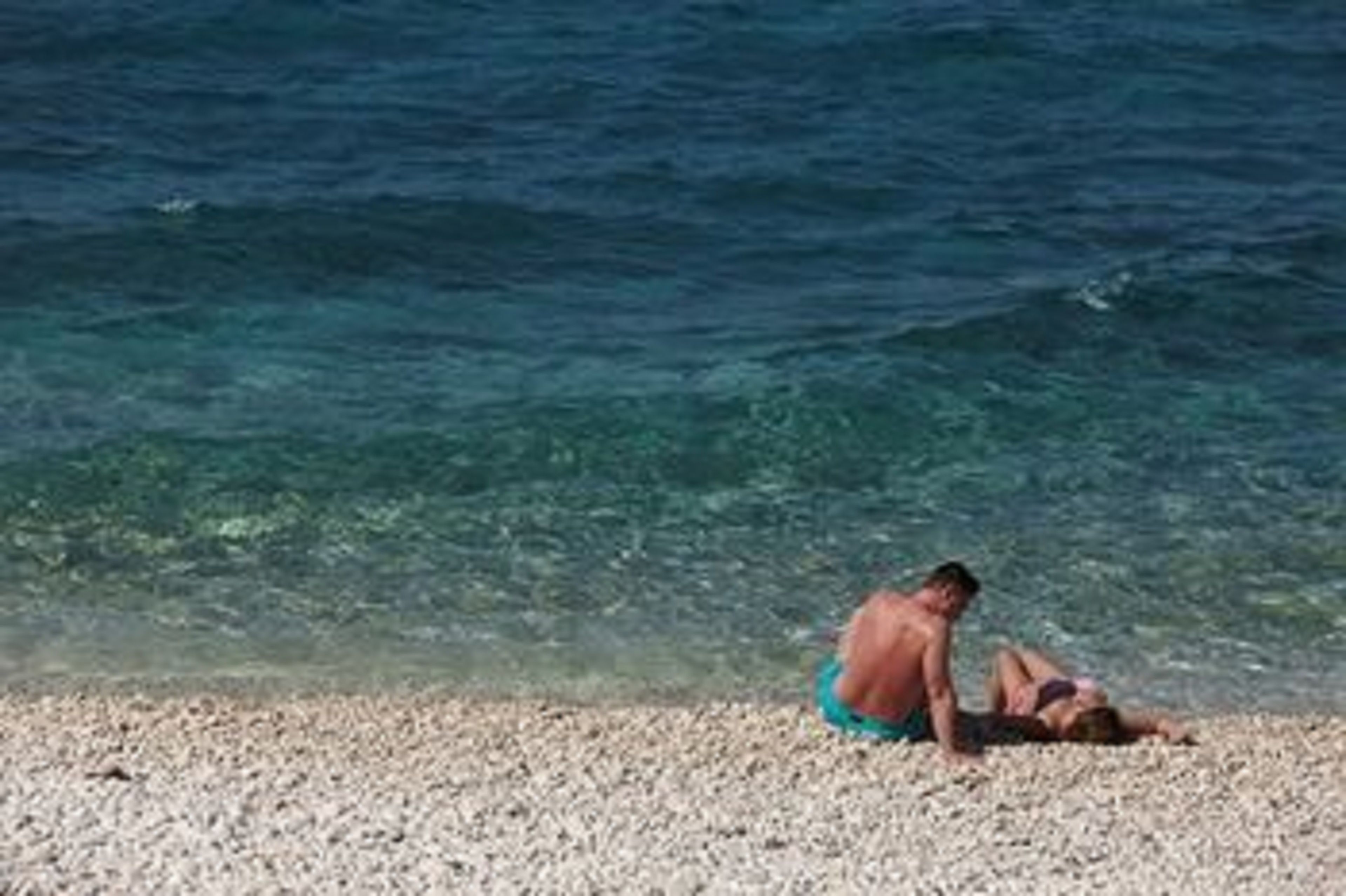 A beach with clear water and a pebbly shore.
