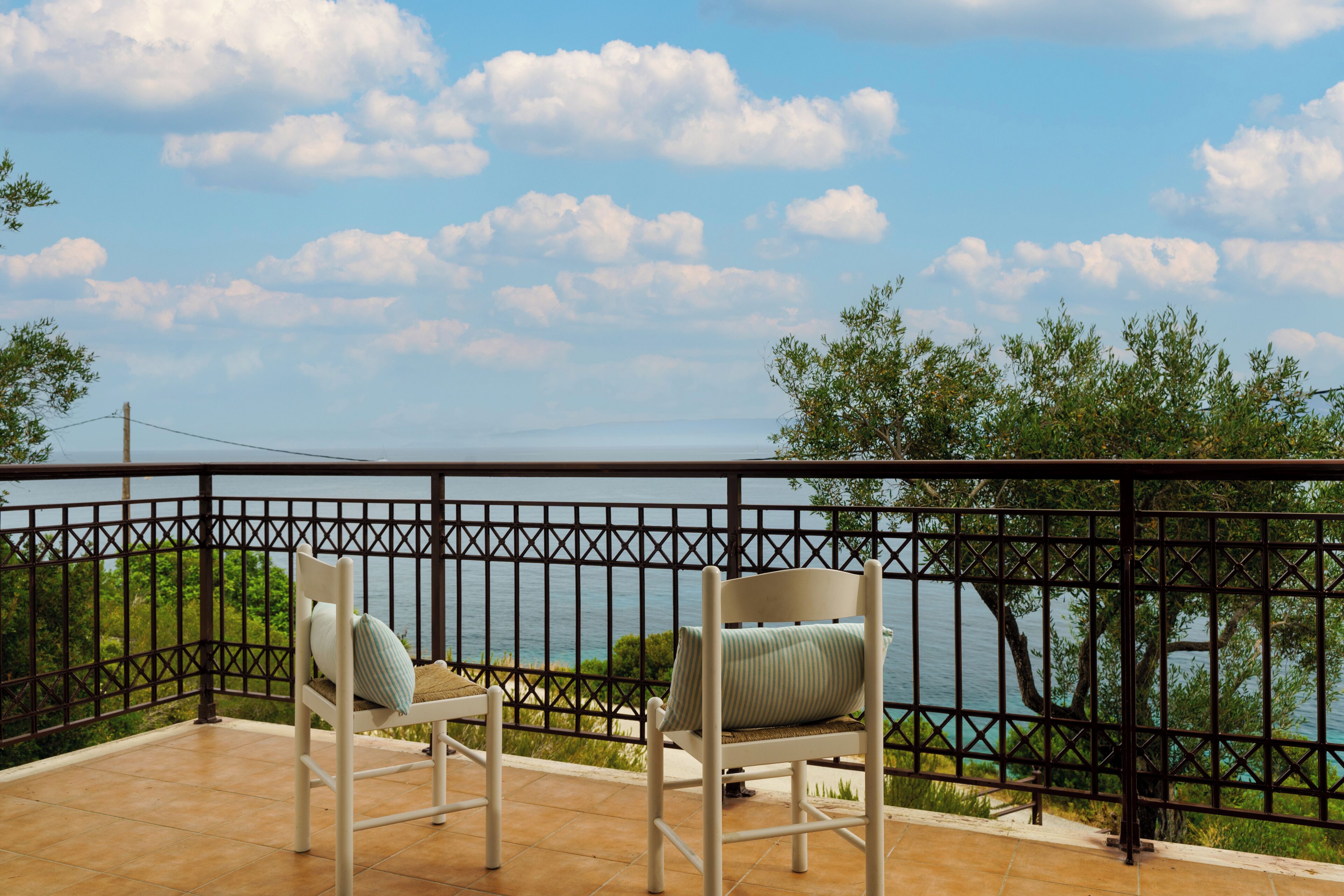 A balcony with two chairs and a view of the sea.