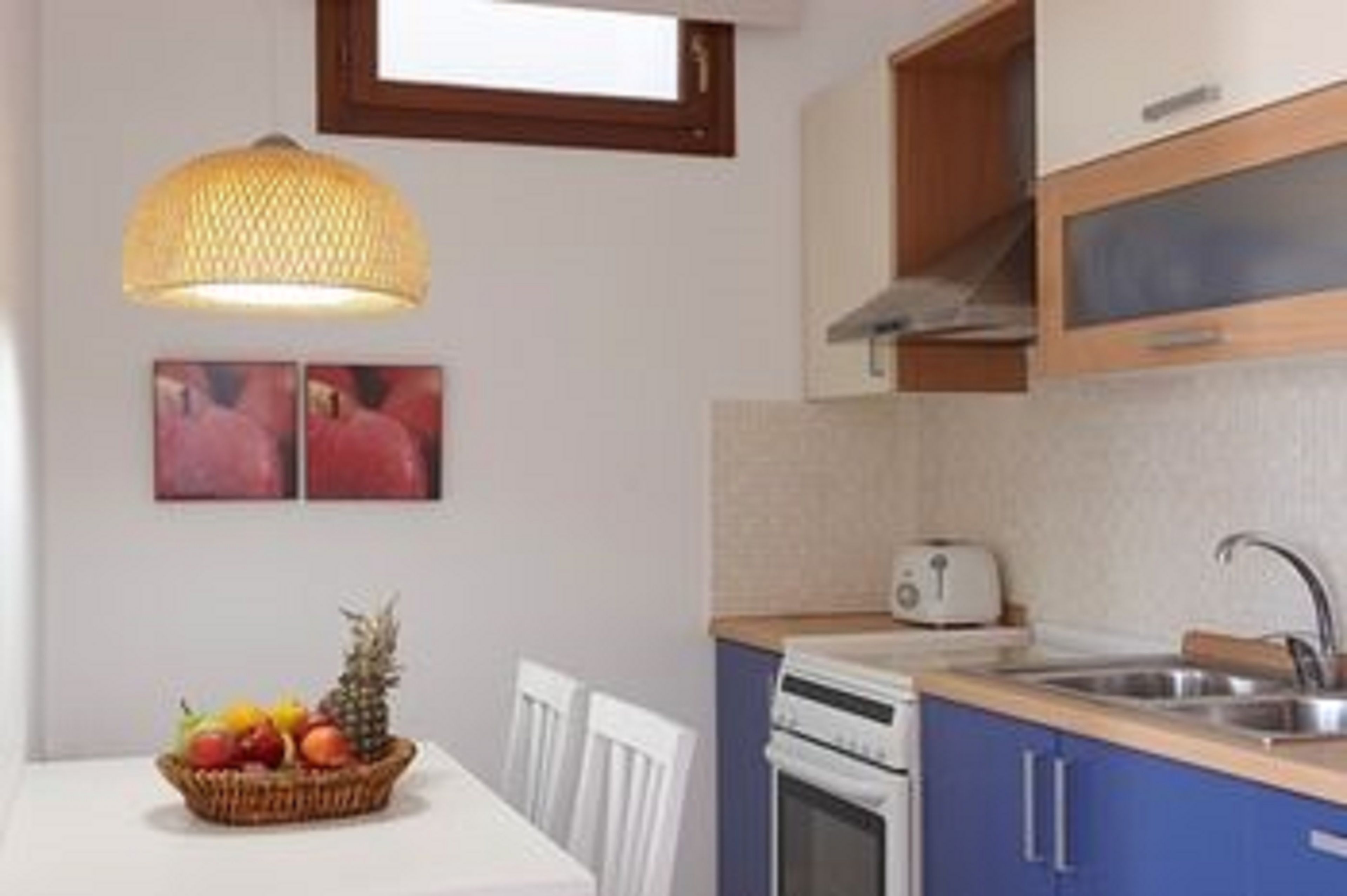 A kitchen with white cabinets, a toaster, and a fruit basket on the table.