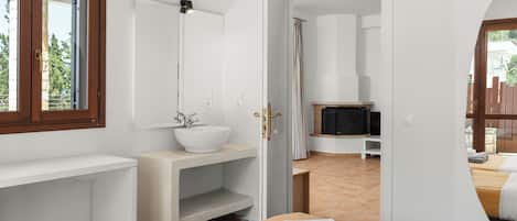 A modern bathroom with a white sink, a mirror, and a shower area.