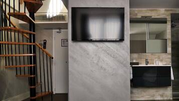 A modern interior with a staircase, a mounted TV, and a bathroom with a shower and sink.
