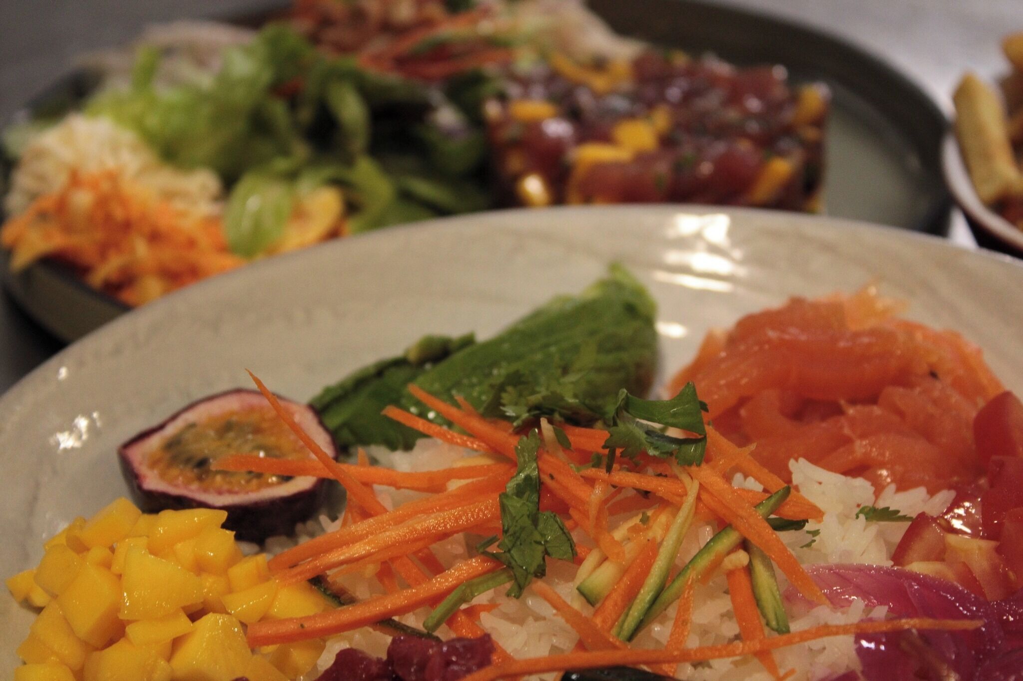 Une assiette de nourriture contenant du riz, de la mangue, des carottes et d’autres l égumes.