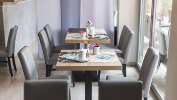 A modern dining area with two tables, each with a white pitcher, red cup, and blue napkins.
