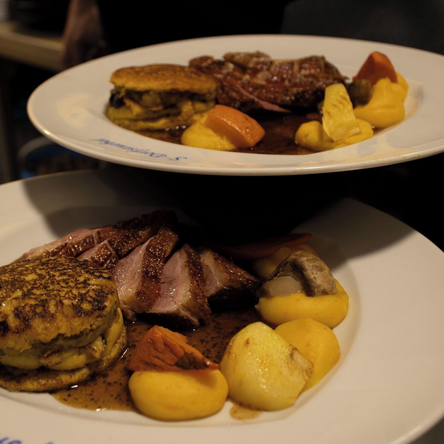 Two plates of food with meat and vegetables.