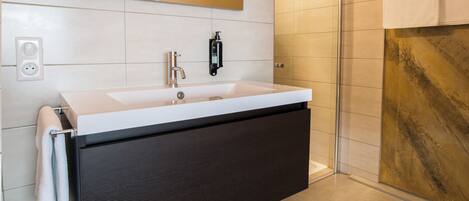 A modern bathroom with a large sink, a mirror, and a shower.