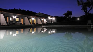 Una piscina al aire libre, sillones reclinables de piscina