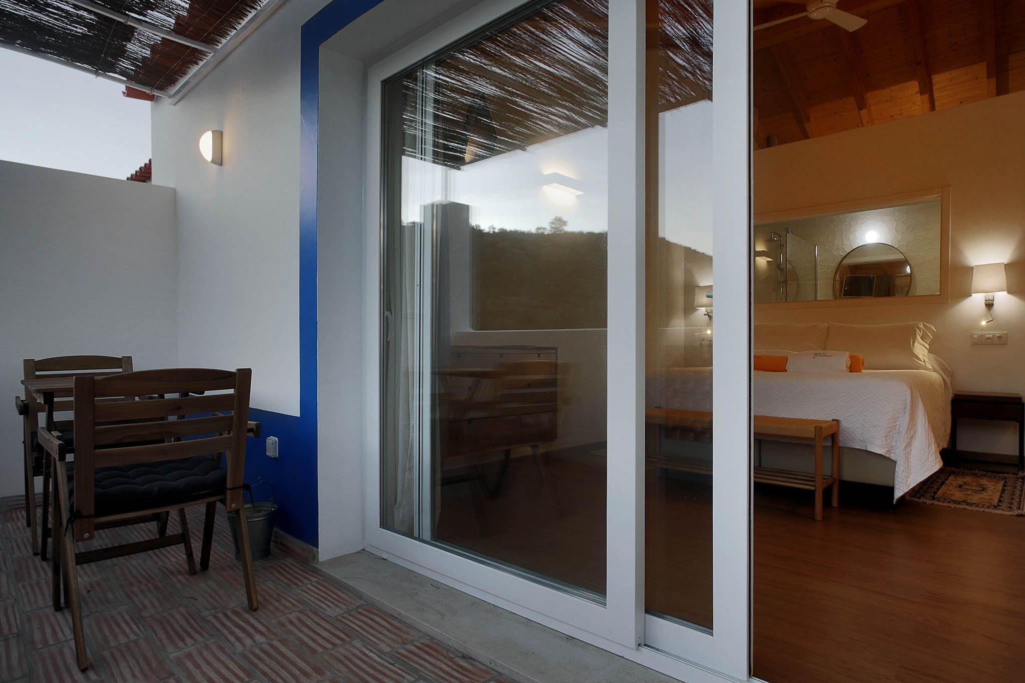 A room with a bed, a bedside table, a mirror, and a window.