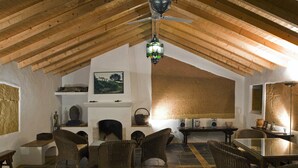 A cozy room with a fireplace, wicker furniture, and a ceiling fan. - Quinta do Chocalhinho (Odemira)