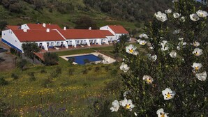 A two-story building with a red roof, a swimming pool, and a garden with various flowers. - Quinta do Chocalhinho (Odemira)
