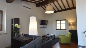 Una sala de estar con un sofá, una mesa de centro, un televisor, una lámpara y un sillón verde.