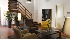 Una sala de estar con una escalera, un sofá, un sillón amarillo, una mesa de centro y una estantería.