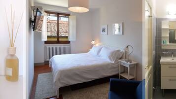 Ein Schlafzimmer mit Bett, Nachttisch, Lampe und einem Badezimmer mit Waschbecken und Spiegel.
