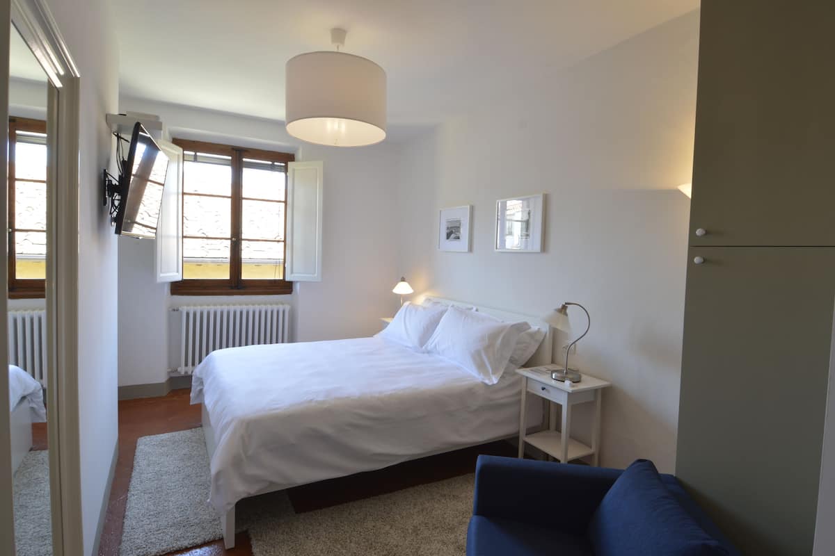 A bedroom with a bed, bedside table, lamp, and a blue chair.