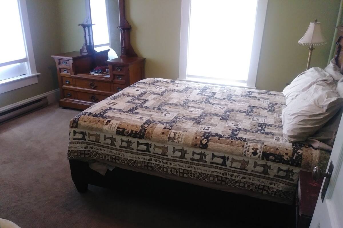 A bedroom with a bed, a dresser, a lamp, and a window.