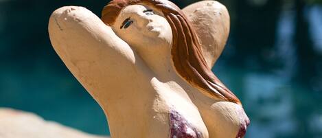 Una escultura de una mujer en traje de baño junto a una piscina.