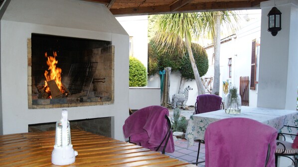 An outdoor patio with a stone fireplace, a zebra statue, and a table with chairs. - GUBAS DE HOEK meet eat sleep (Robertson)
