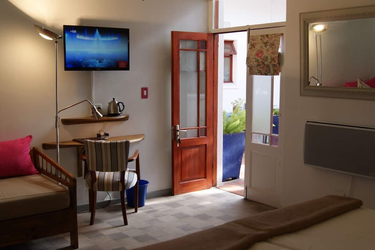 A living room with a sofa, a television mounted on the wall, a wooden door, and a mirror.