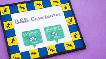 A framed recommendation sign for B&B Casa Huarez, featuring lizard icons and text in Spanish.