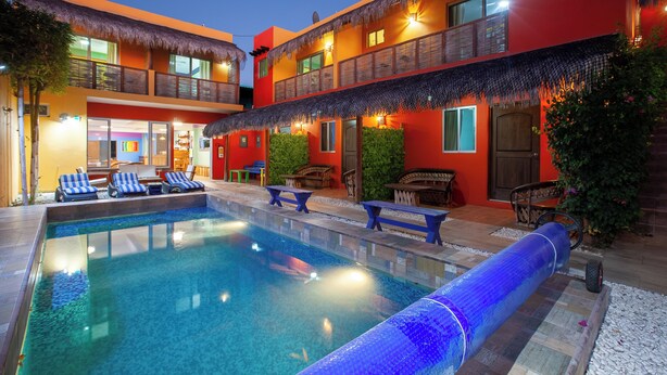 A hotel with a swimming pool, lounge chairs, and a thatched roof. - B&B Casa Juarez (La Paz)