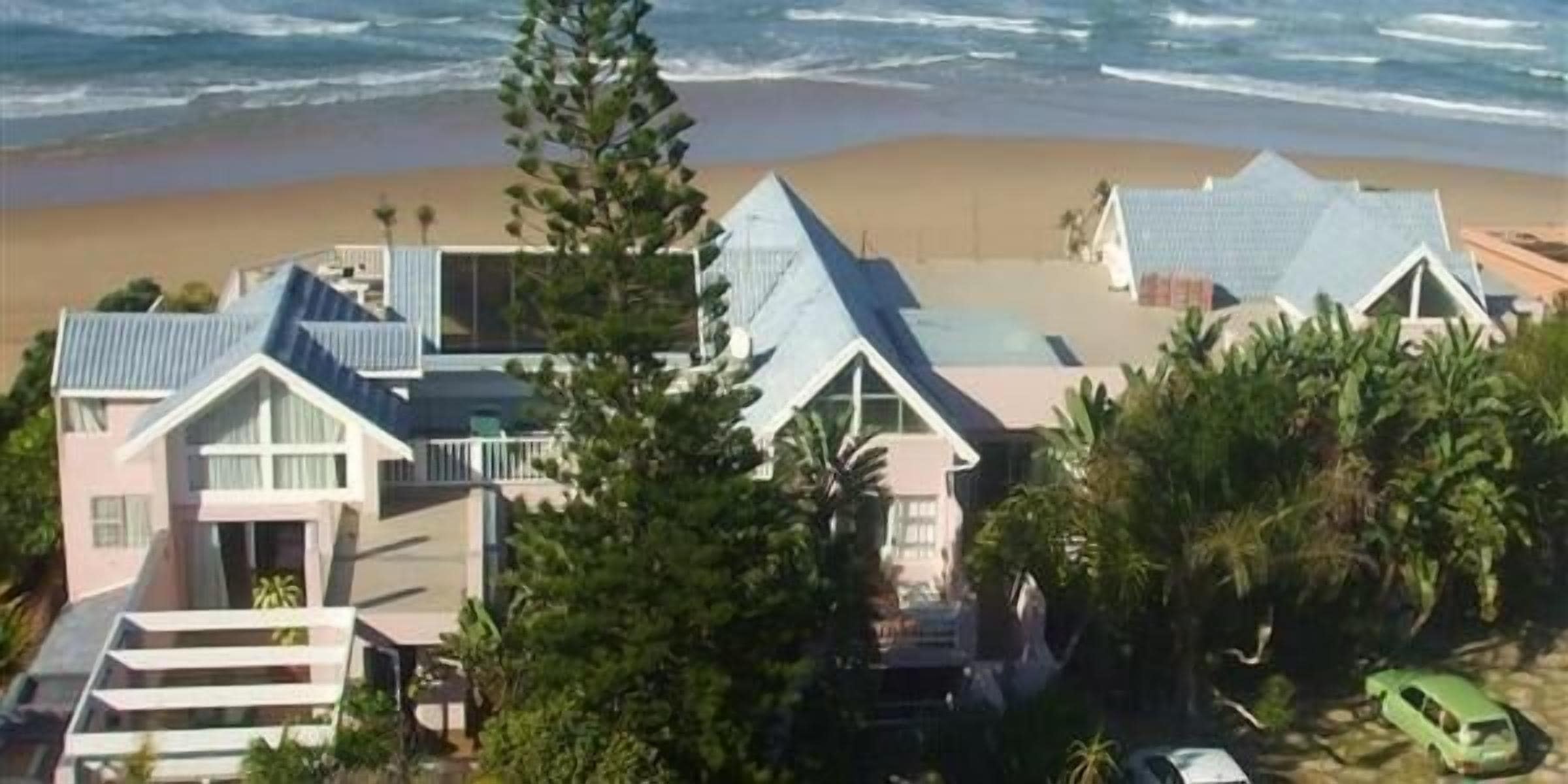 A coastal property with multiple buildings, including a house with a large balcony and a smaller structure with a sloped roof.