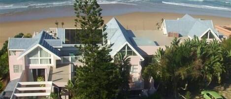A coastal property with multiple buildings, including a house with a large balcony and a smaller structure with a sloped roof.