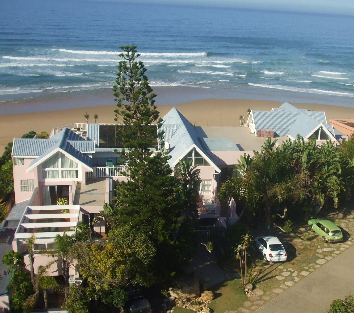A beachfront property with multiple houses, a driveway, and a car parked on the street.