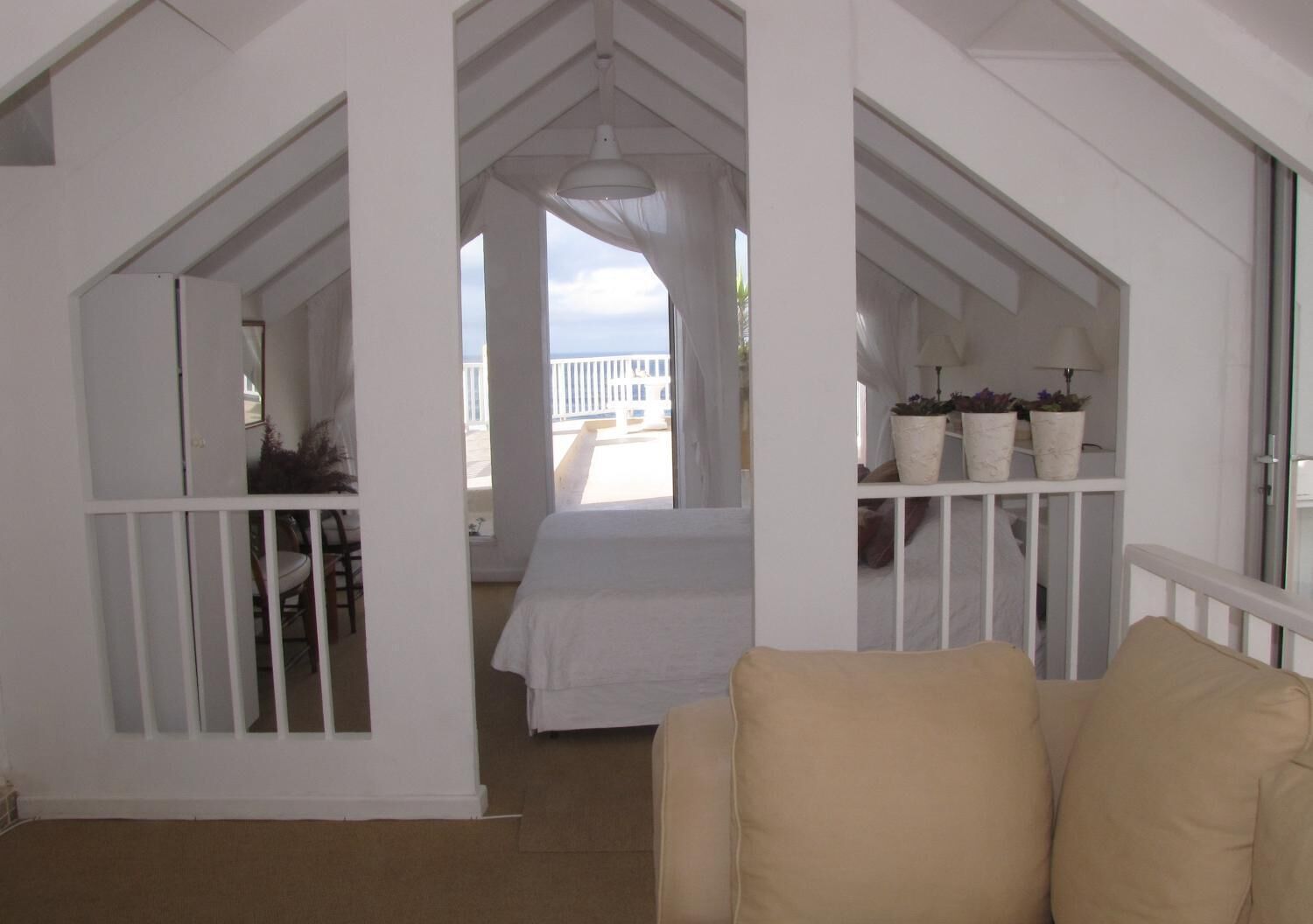 Una habitación con una cama, baranda blanca y vistas al balcón.