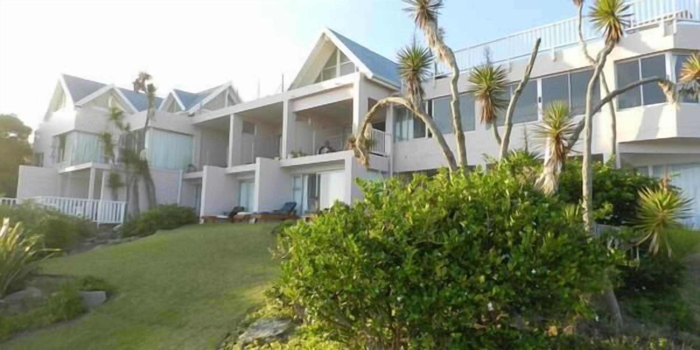 A multi-story hotel with balconies and a well-maintained lawn.