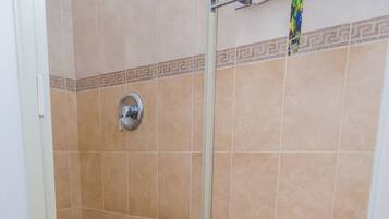 A bathroom with a toilet, shower, and a towel rack.