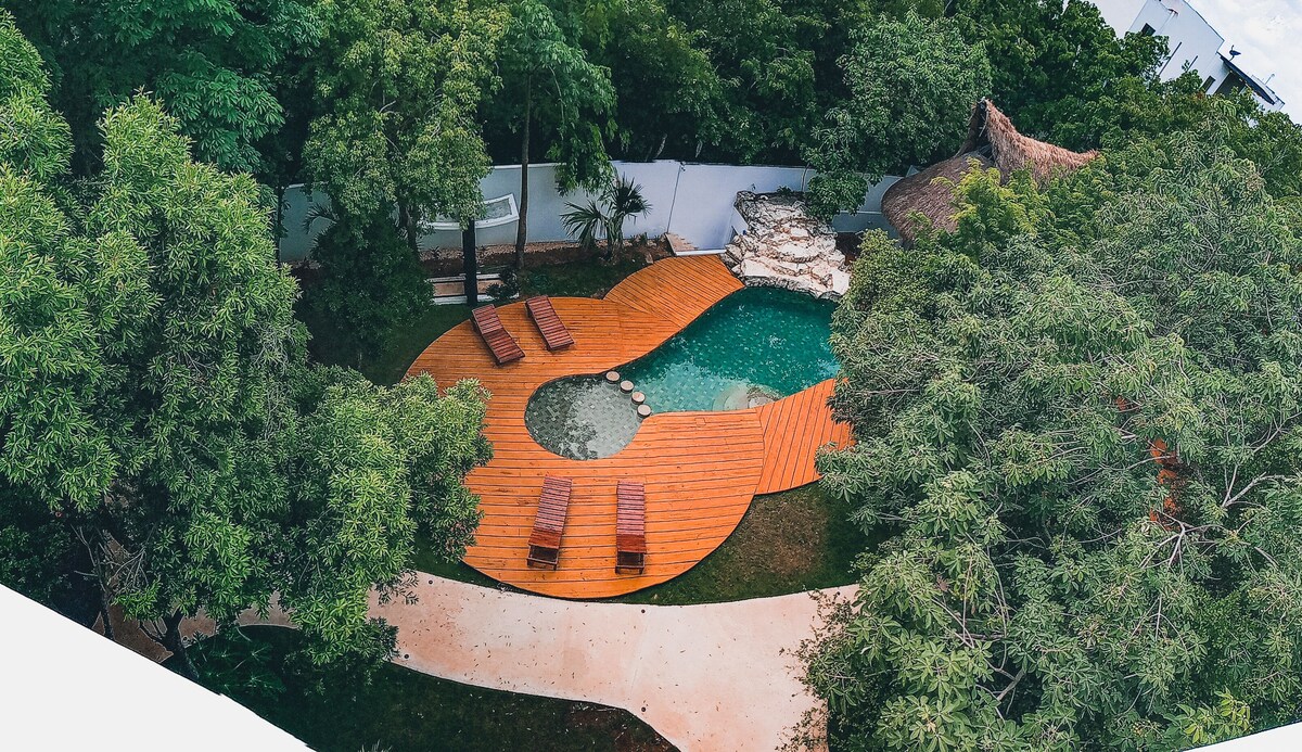 drone shot of pool area of Coco Village, with lots of greenery around the hotel