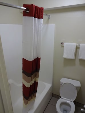 A bathroom with a shower curtain, a toilet, and a towel rack.