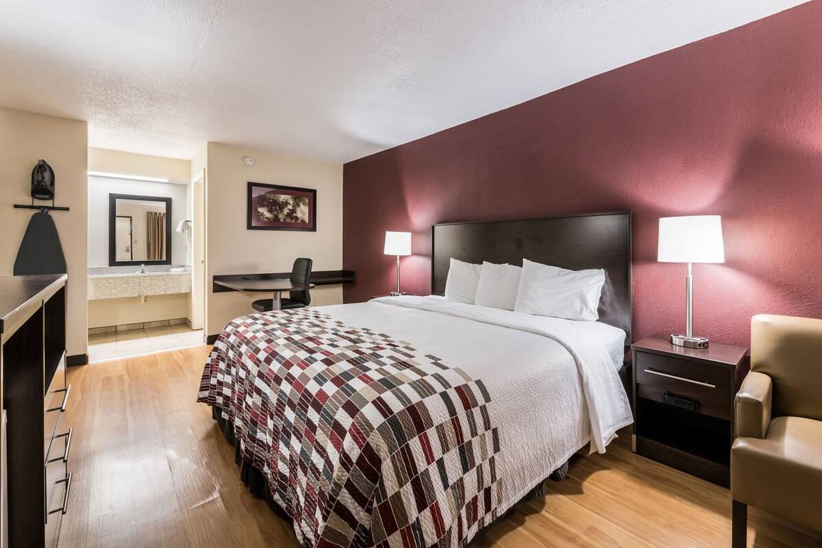 A hotel room with a bed, desk, chair, and nightstand.