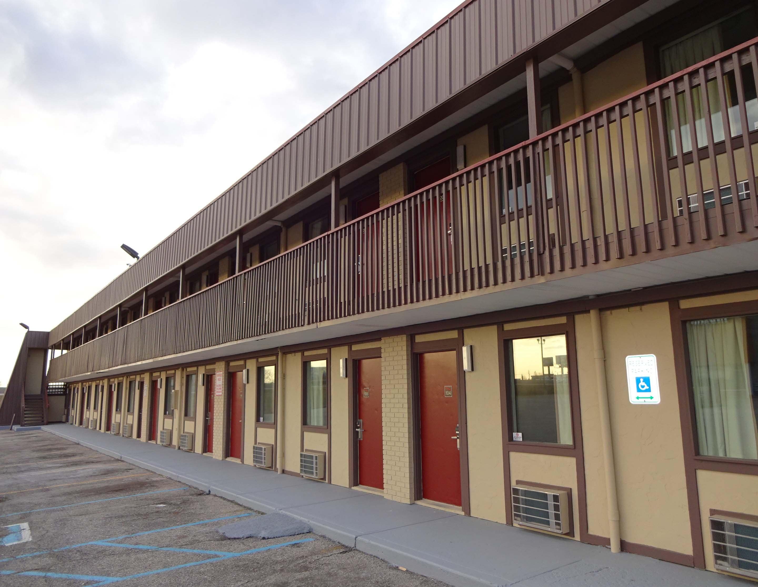 A motel with a two-story structure, multiple rooms, and a parking lot.