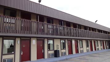 A motel with multiple rooms, each with a door number, a small air conditioning unit, and a balcony.