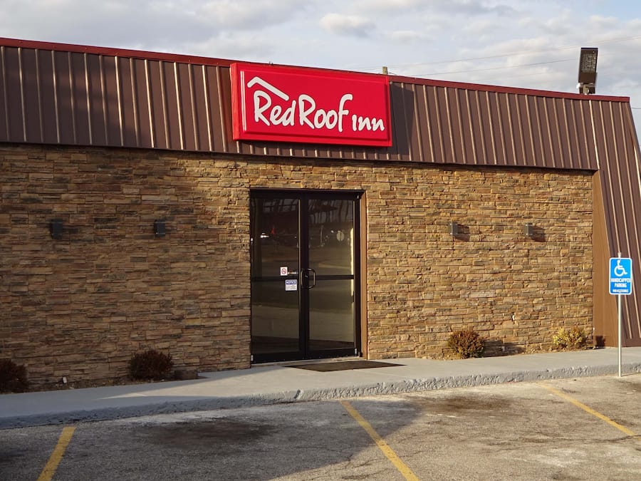 A RedRoof Inn building with a stone facade, a black entrance door, and a handicap parking sign.