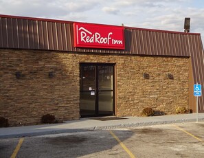 A RedRoof Inn building with a stone facade, a black entrance door, and a handicap parking sign.