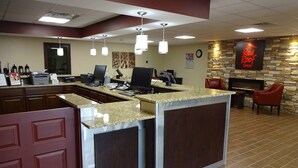 A reception area with a counter, computers, and a stone wall with a fireplace.