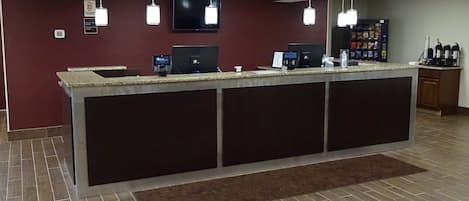 Un espace d’accueil comprenant un comptoir, des ordinateurs et une machine à café.