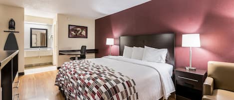 A hotel room with a bed, bedside lamps, a desk, and a chair.