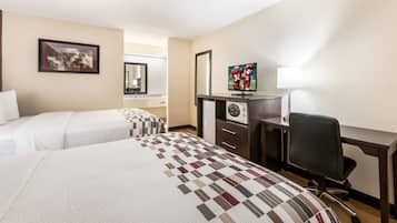 A hotel room with two beds, a desk with a computer, a chair, and a television.