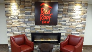 A Red Roof Inn lobby with a stone wall, a fireplace, and two leather chairs.