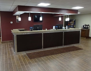 Un área de recepción con mostrador, televisor y máquina de café.