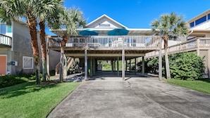A beachfront property with a covered patio, palm trees, and a clear blue sky. - Redecorated Pet Friendly Home by RedAwning (Fernandina Beach)